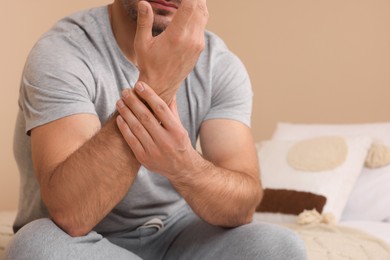 Man suffering from pain in his hand on bed indoors, closeup