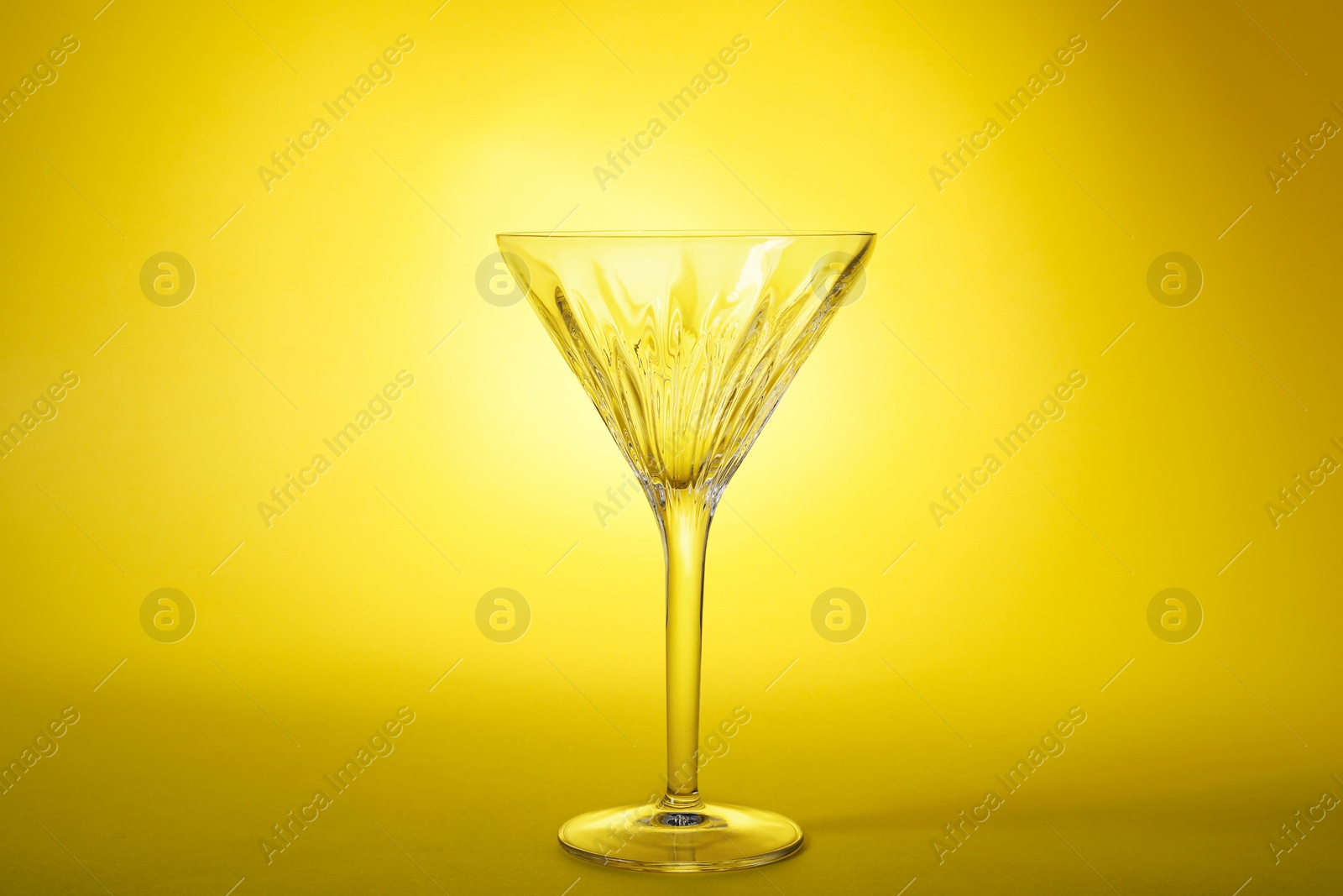 Photo of Elegant empty martini glass on yellow background