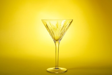 Elegant empty martini glass on yellow background