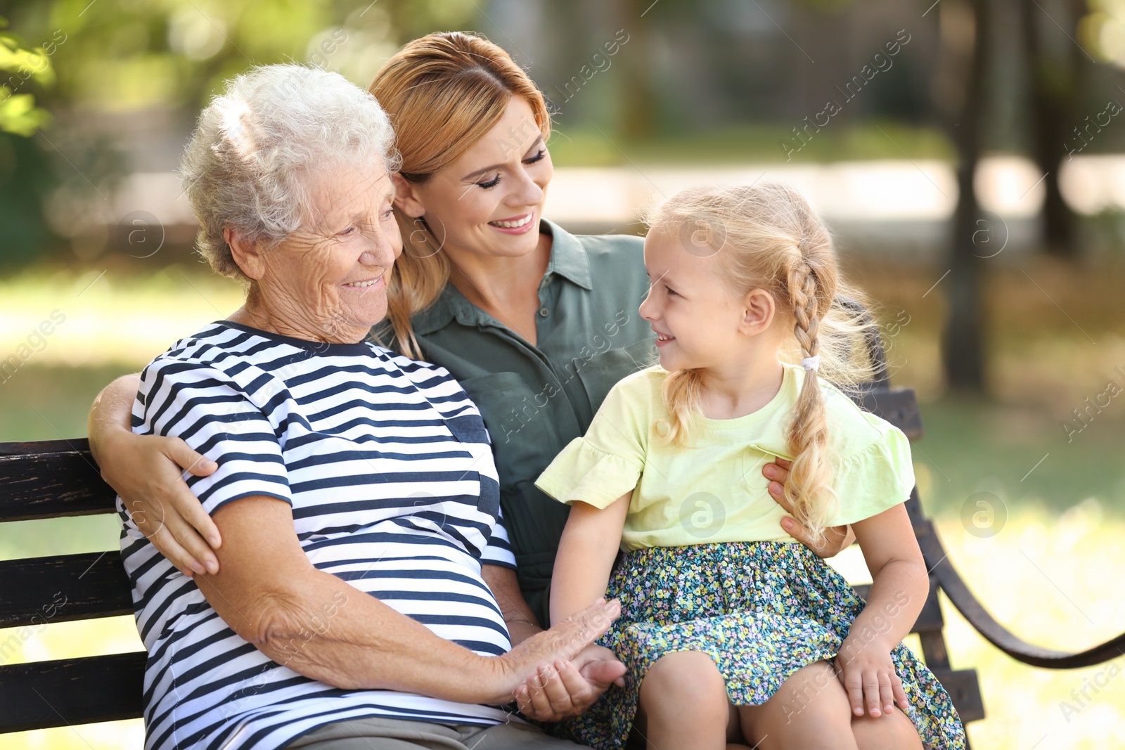 Photo of Woman with daughter and elderly mother on bench in park