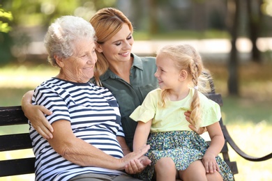 Photo of Woman with daughter and elderly mother on bench in park