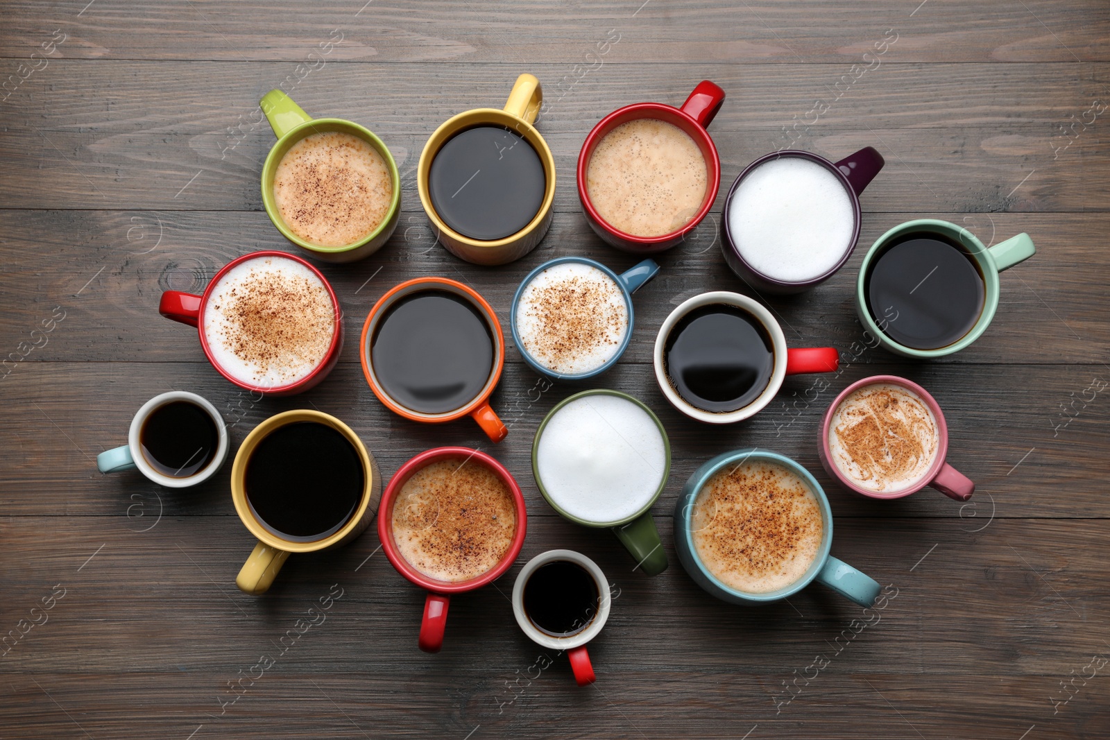 Photo of Many different cups with aromatic hot coffee on wooden table, flat lay