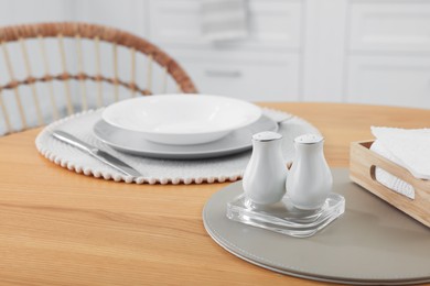 Photo of White ceramic salt and pepper shakers on wooden table in kitchen, space for text