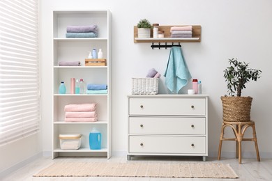 Photo of Shelving unit with stacked clean towels and toiletries in room