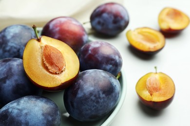 Tasty ripe plums on white table, closeup