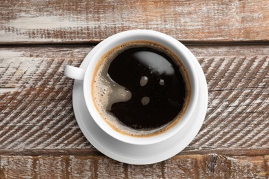 Cup of aromatic coffee on wooden table, top view