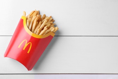 Photo of MYKOLAIV, UKRAINE - AUGUST 12, 2021: Big portion of McDonald's French fries on white wooden table, top view. Space for text