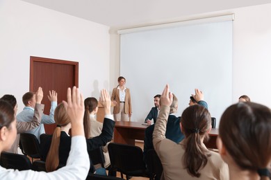 Photo of People raising hands to ask questions at business conference in meeting room