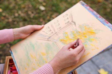 Photo of Woman drawing with soft pastels outdoors, closeup