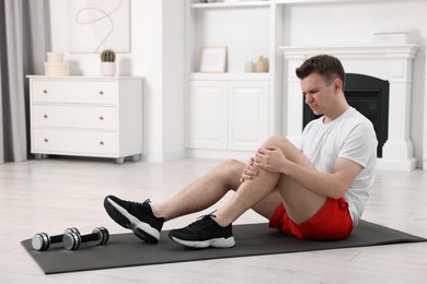 Photo of Man suffering from leg pain on mat at home