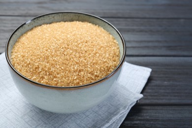 Photo of Brown sugar in bowl on black wooden table, closeup