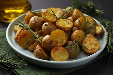 Delicious baked potatoes with rosemary on plate, closeup