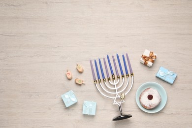Photo of Flat lay composition with Hanukkah menorah and gift boxes on light wooden table. Space for text