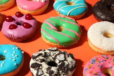 Sweet tasty glazed donuts on coral background