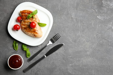Tasty grilled chicken fillets served on grey table, flat lay. Space for text