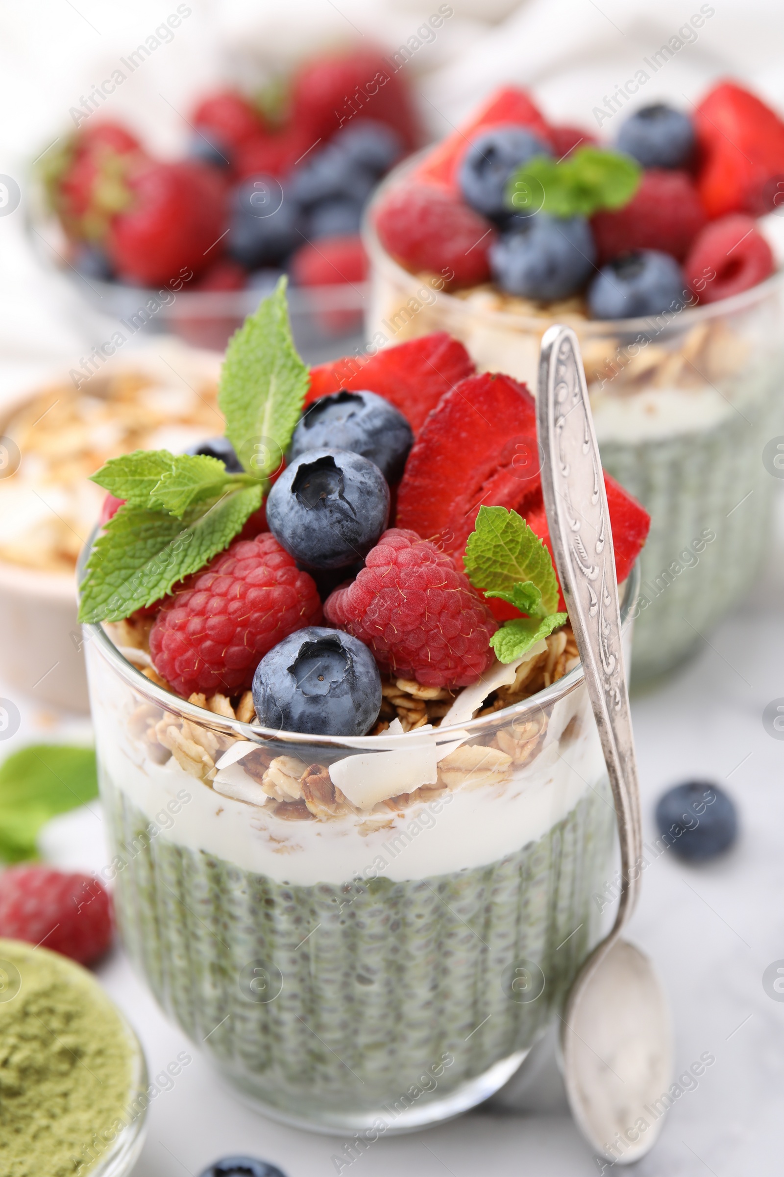 Photo of Tasty matcha chia pudding with oatmeal and berries on white marble table, closeup. Healthy breakfast