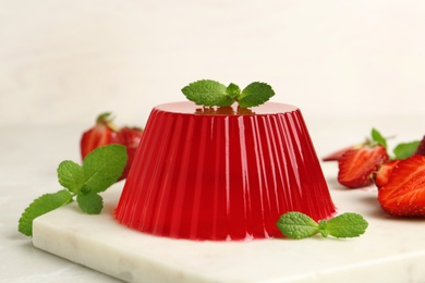 Photo of Stone board with fruit jelly, strawberries and mint on light table