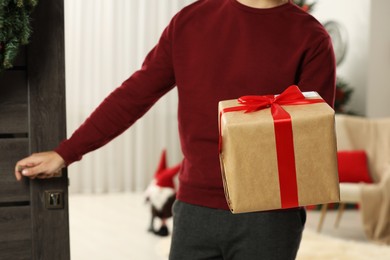 Young man in Santa hat with Christmas gift box received by mail indoors, closeup