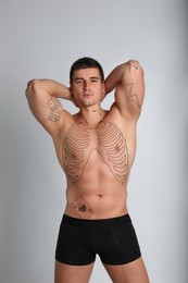 Image of Handsome man with beautiful tattoo sketches on light background