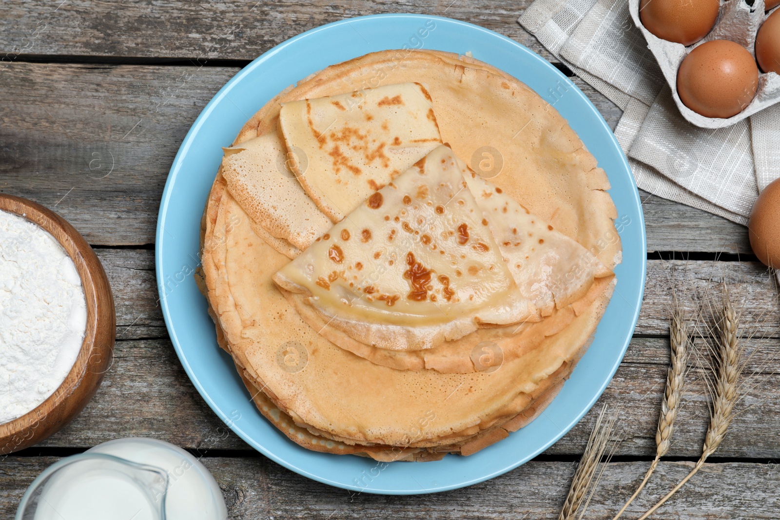 Photo of Delicious crepes and ingredients on wooden table, flat lay