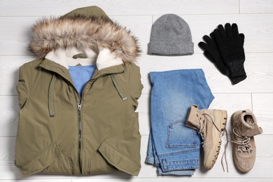 Flat lay composition with warm clothes for winter vacation on wooden background