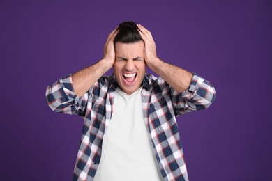 Portrait of stressed man on purple background