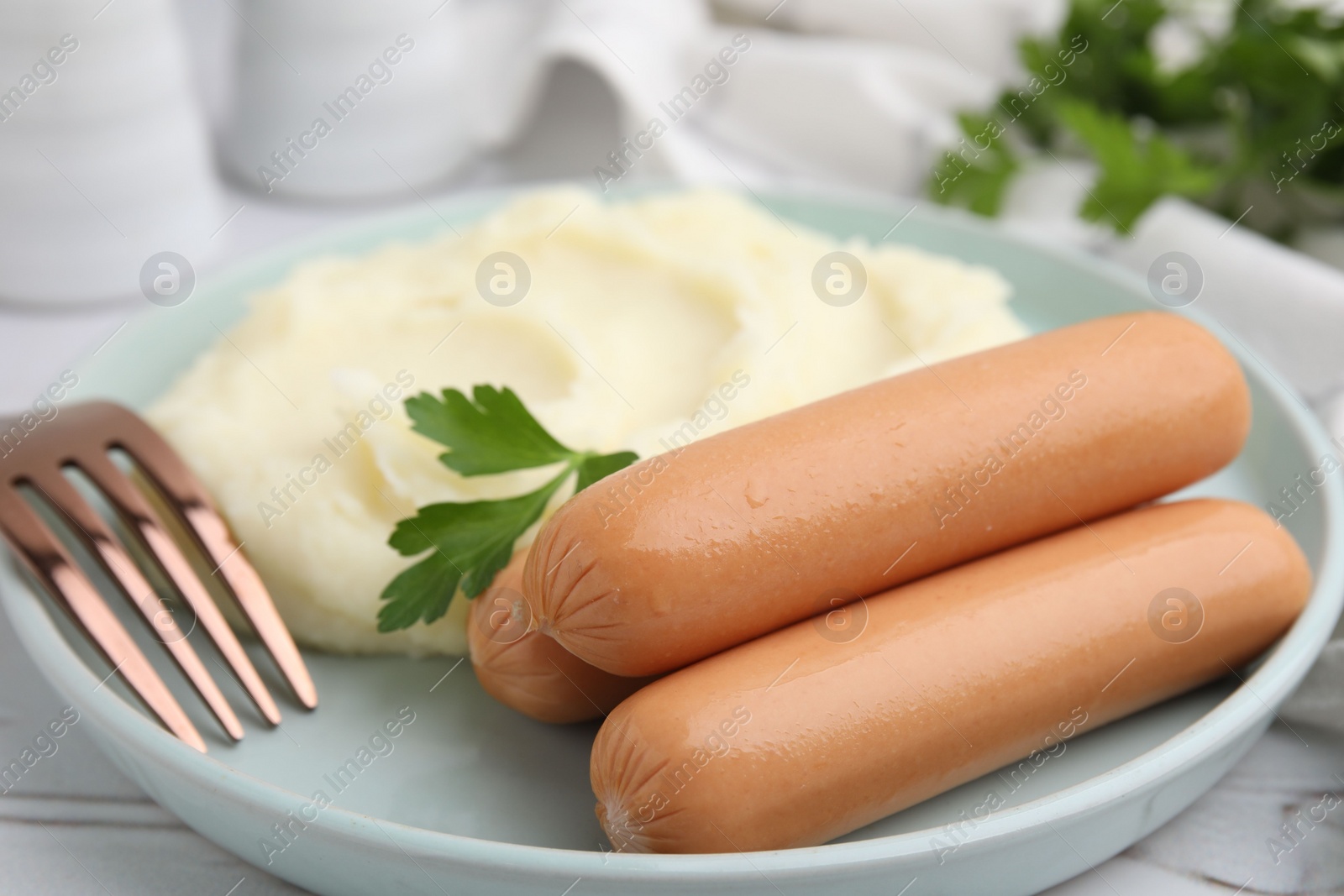 Photo of Delicious boiled sausages, mashed potato, parsley and fork on table, closeup