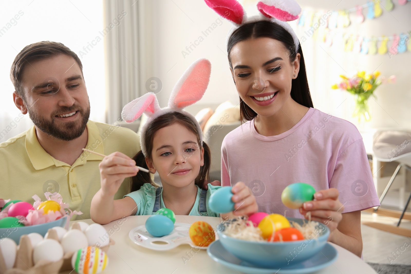 Photo of Happy family painting Easter eggs at table indoors