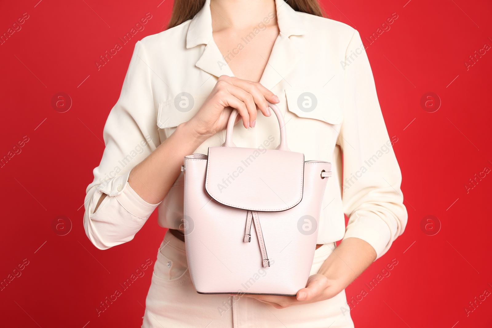 Photo of Young woman in casual outfit with stylish bag on red background, closeup