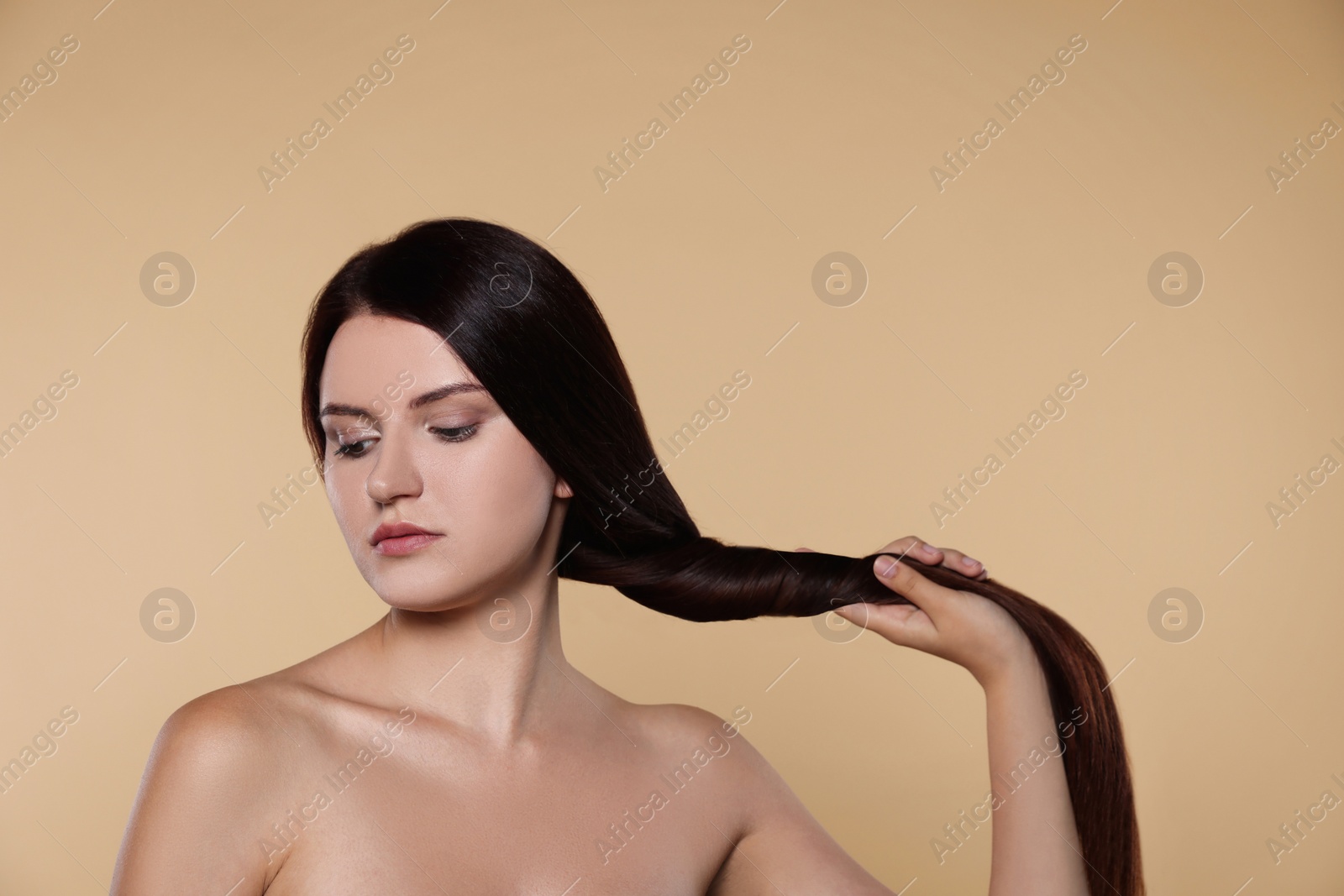 Photo of Portrait of beautiful young woman with healthy strong hair on beige background