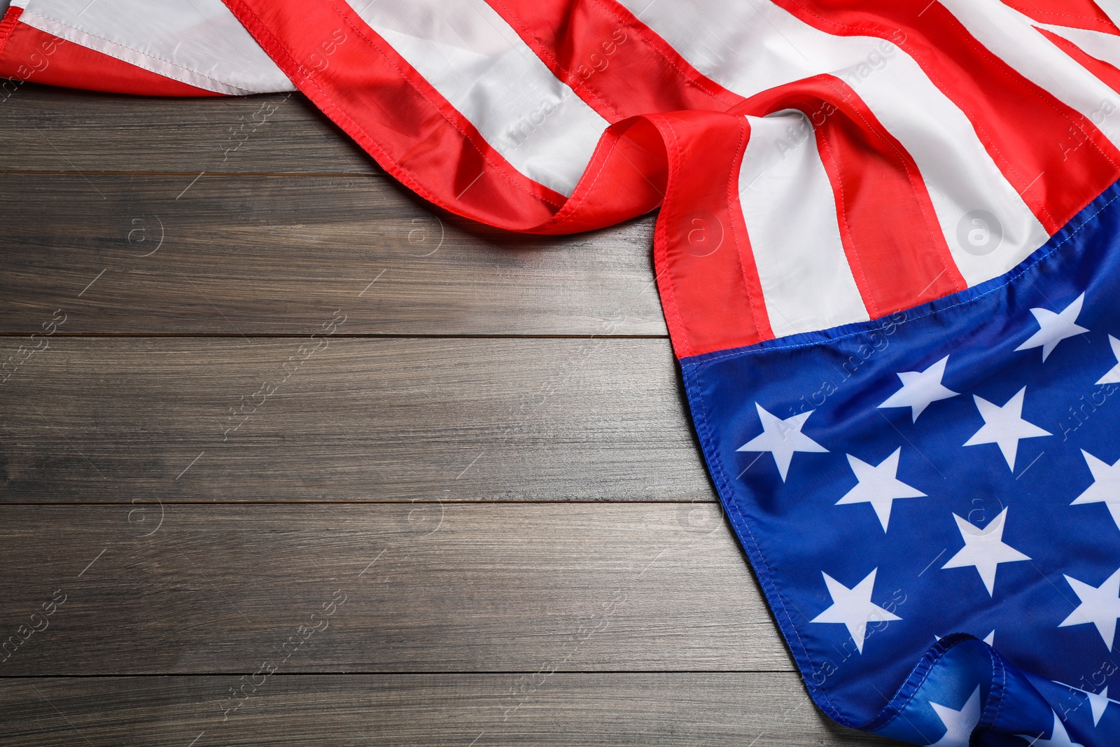 Photo of American flag on wooden table, top view. Space for text