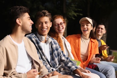 Group of happy young students having fun together in park