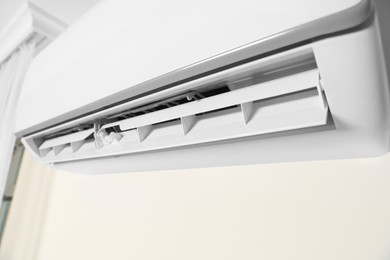 Photo of Modern air conditioner on white wall indoors, closeup view