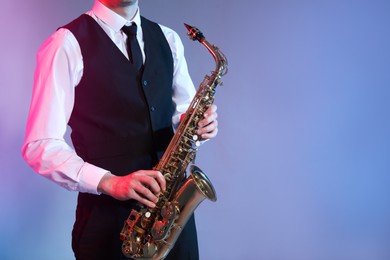 Man in elegant outfit playing saxophone on color background, closeup. Space for text