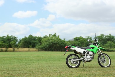 Photo of Stylish cross motorcycle on green grass outdoors, space for text