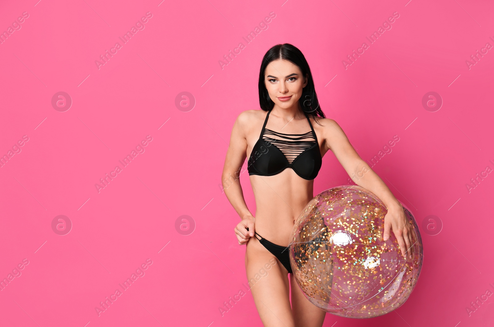 Photo of Beautiful young woman in stylish bikini with beach ball on pink background. Space for text