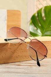 Photo of Stylish sunglasses on white wooden table. Summer accessory