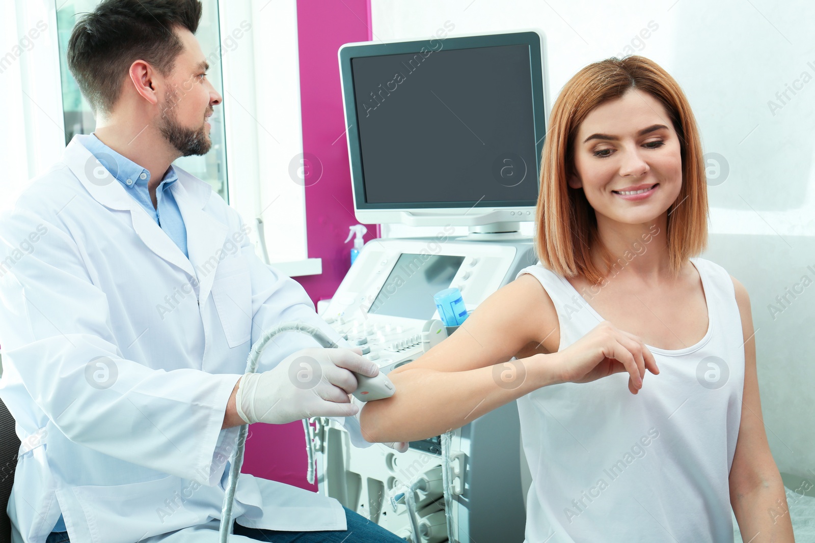 Photo of Doctor conducting ultrasound examination of elbow joint in clinic. Space for text