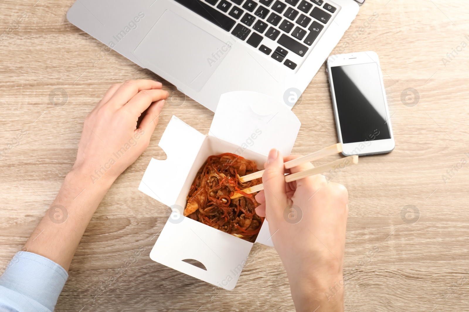 Photo of Woman eating Chinese noodles at workplace, closeup with space for text. Food delivery