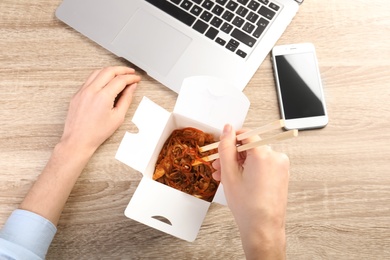 Photo of Woman eating Chinese noodles at workplace, closeup with space for text. Food delivery