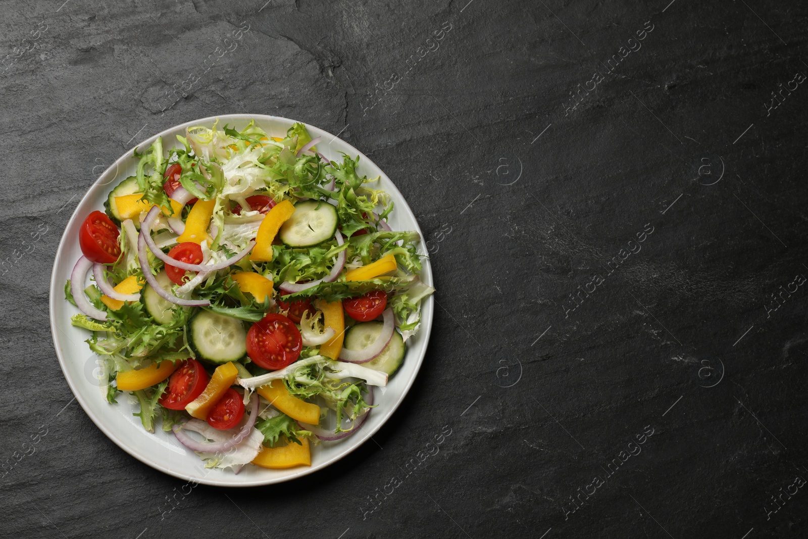 Photo of Tasty fresh vegetarian salad on black table, top view. Space for text