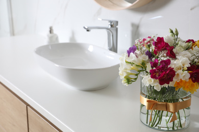 Beautiful bouquet with spring freesia flowers in bathroom, space for text