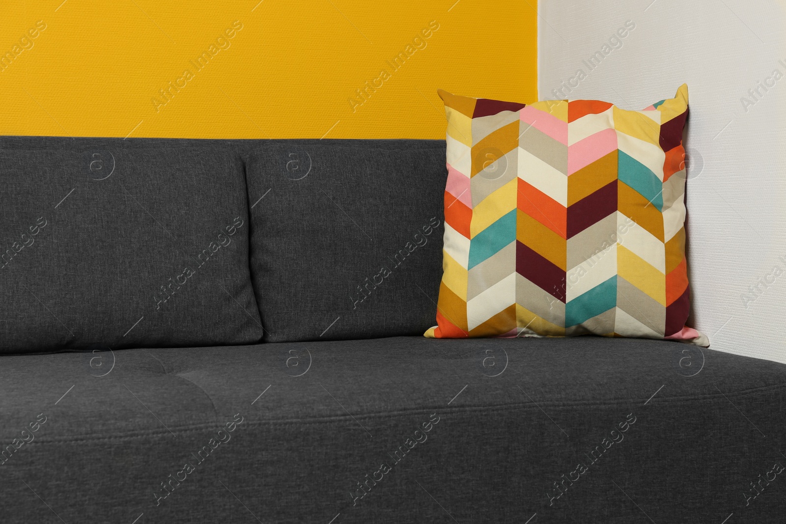 Photo of Bright cushion on grey sofa in room