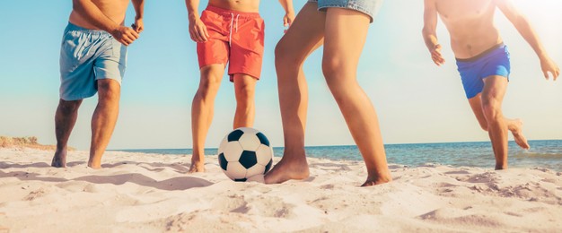 Image of Friends playing football on beach during sunny day, closeup. Banner design