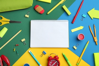 Photo of Different bright school stationery and blank notebook on color background, flat lay. Space for text