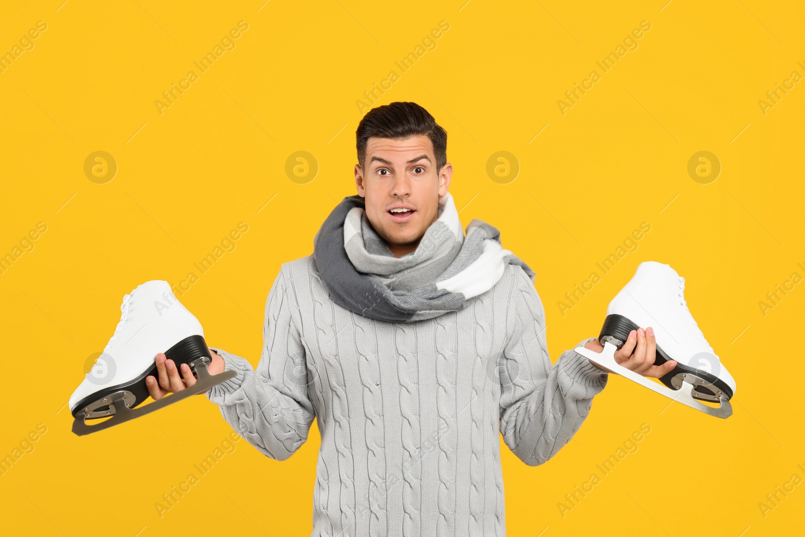 Photo of Emotional man with ice skates on yellow background