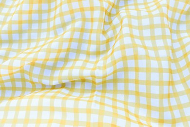 Yellow checkered picnic tablecloth as background, closeup