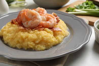 Photo of Plate with fresh tasty shrimps, bacon, grits and green onion on white table, closeup