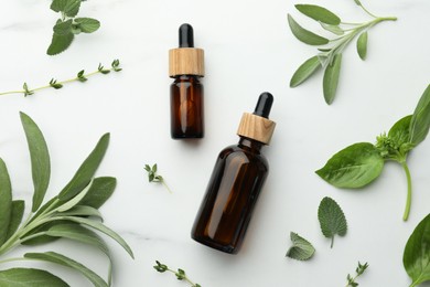 Photo of Bottles of essential oils and fresh herbs on white marble table, flat lay
