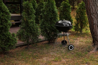 Photo of New barbecue grill near green trees in garden